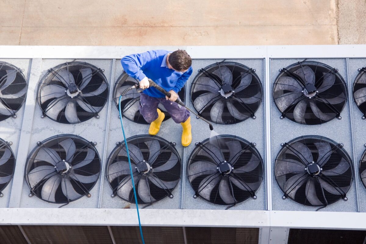 Technician cleaning rooftop industrial HVAC fans in Boston MA